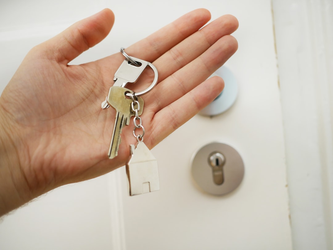 Person holding set of house keys with house-shaped keyring for key holding service in Charente